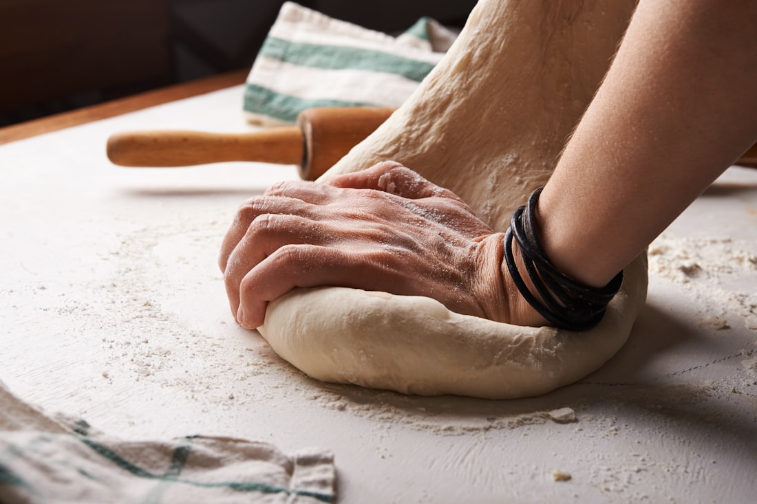 A baker kneading fresh dough by hand